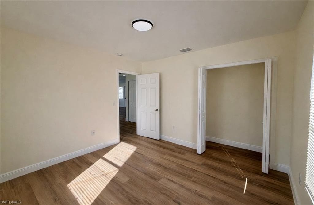 Unfurnished bedroom with wood finished floors and baseboards