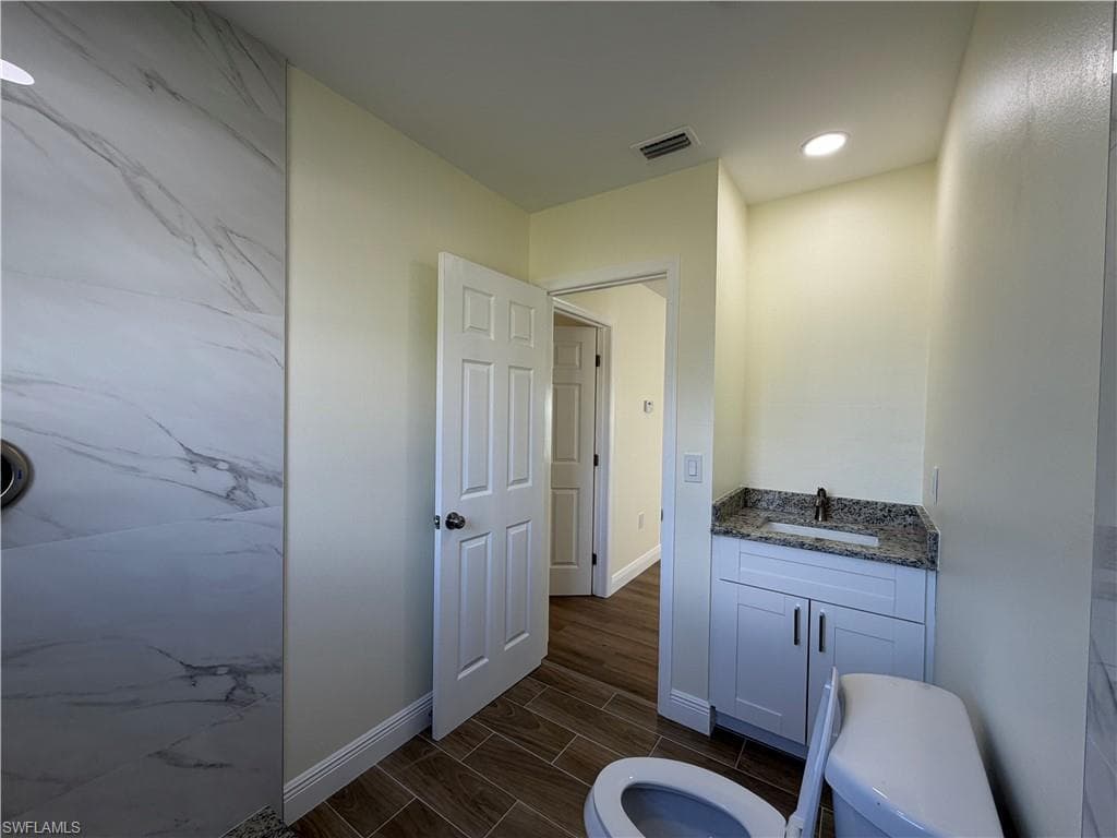 Full bath featuring vanity, wood finish floors, and recessed lighting