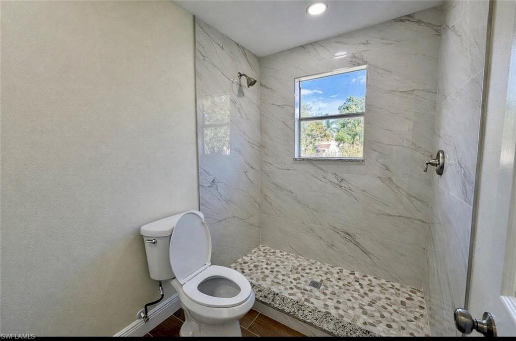 Bathroom with a marble finish shower and toilet