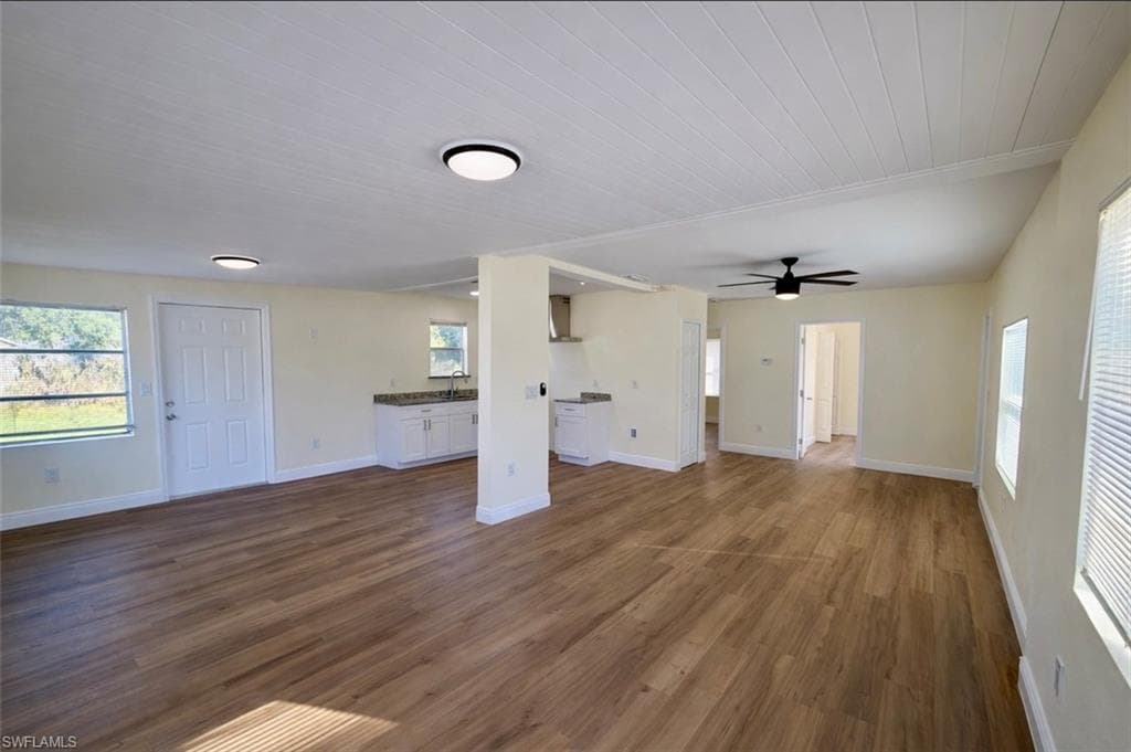 Unfurnished living room with plenty of natural light, dark wood finished floors, and ceiling fan