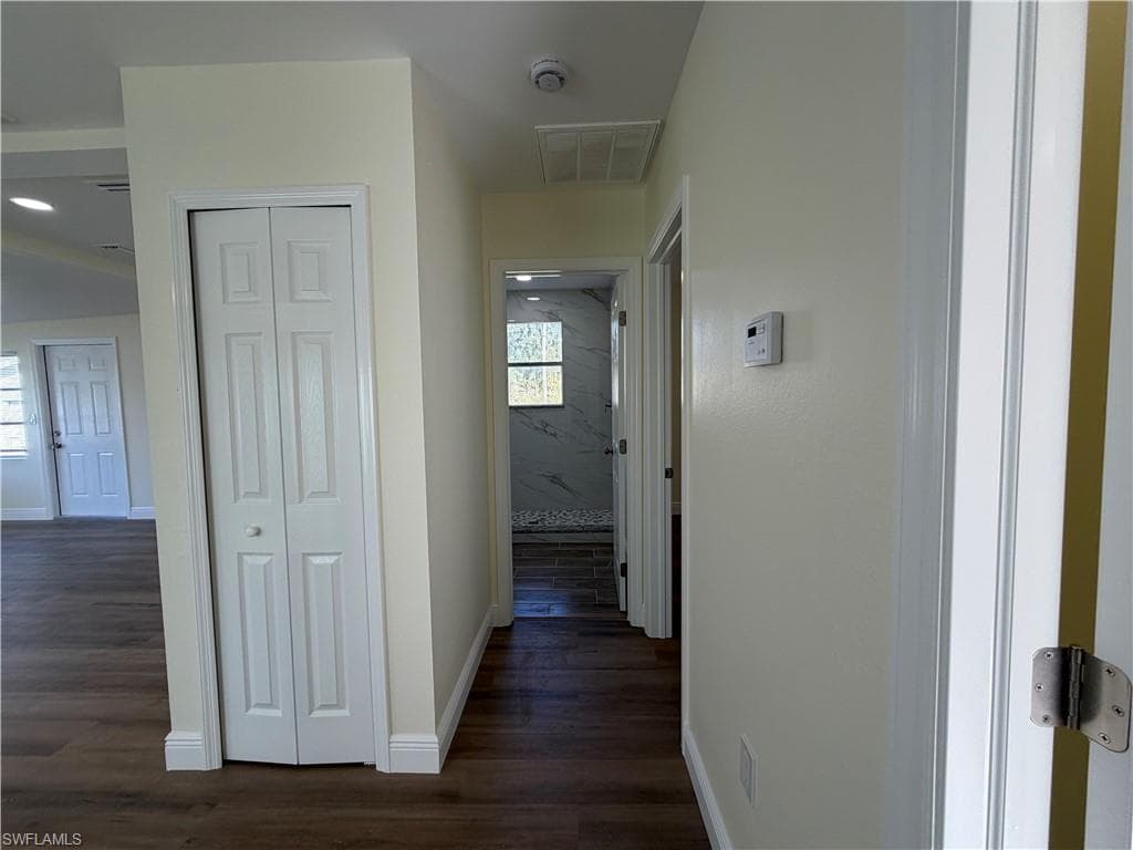 Hallway featuring baseboards and dark wood-type flooring