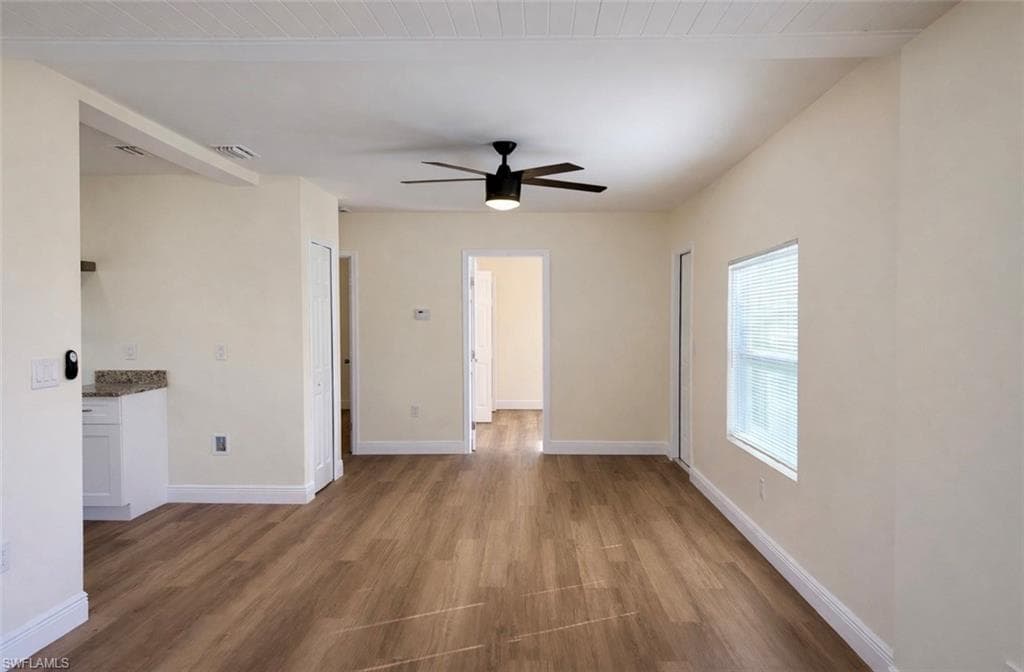 Empty room featuring dark wood-type flooring, ceiling fan, and wooden ceiling