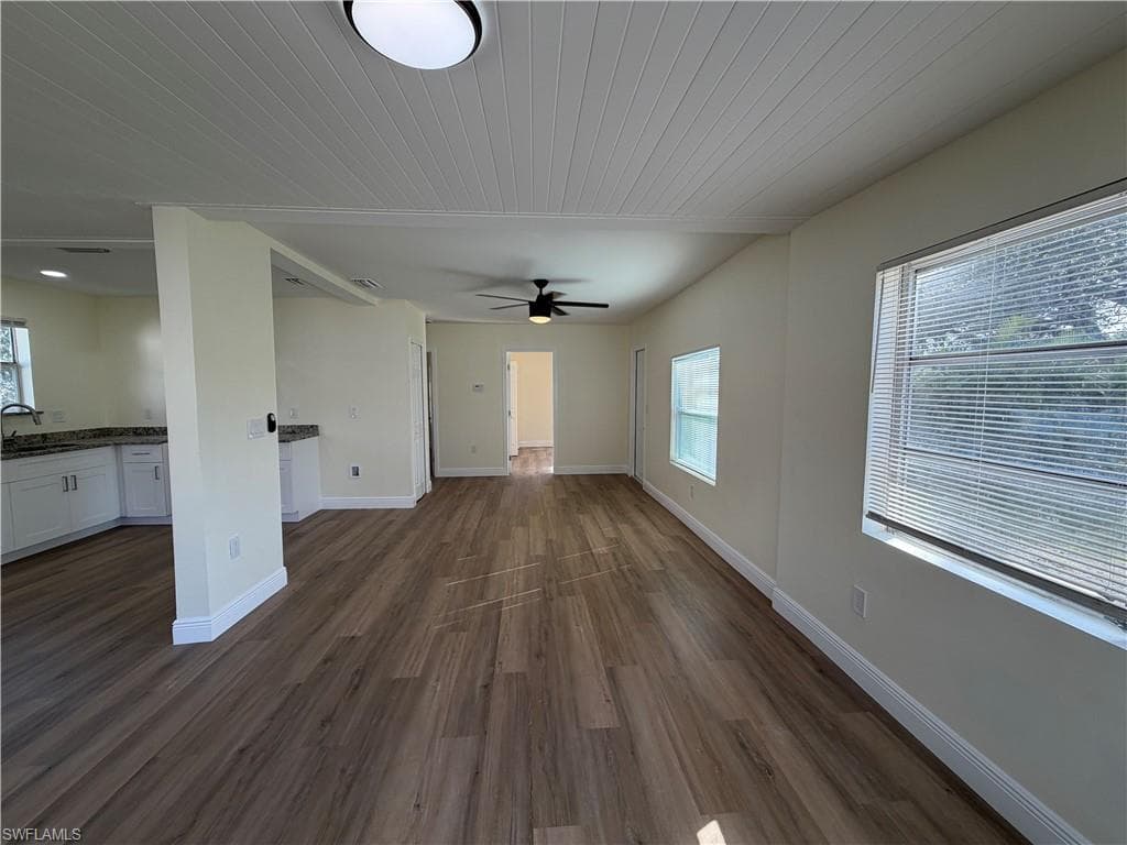 Unfurnished living room with dark wood finished floors, wood ceiling, and a ceiling fan