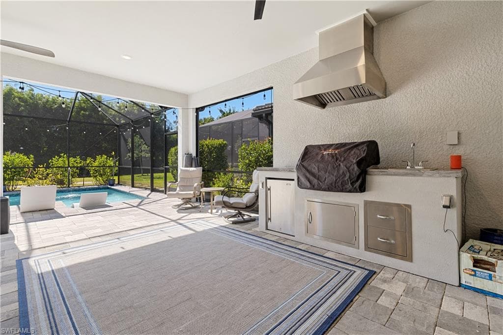 View of patio / terrace with a sunroom, an outdoor kitchen, an outdoor pool, a ceiling fan, and glass enclosure