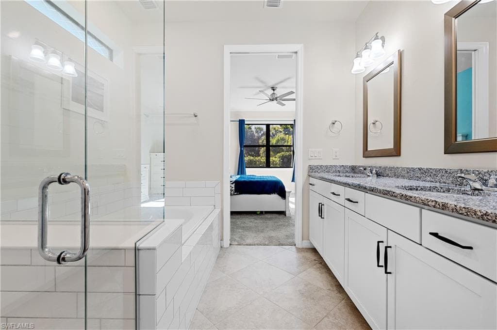 Full bath featuring connected bathroom, plenty of natural light, double vanity, and a shower stall