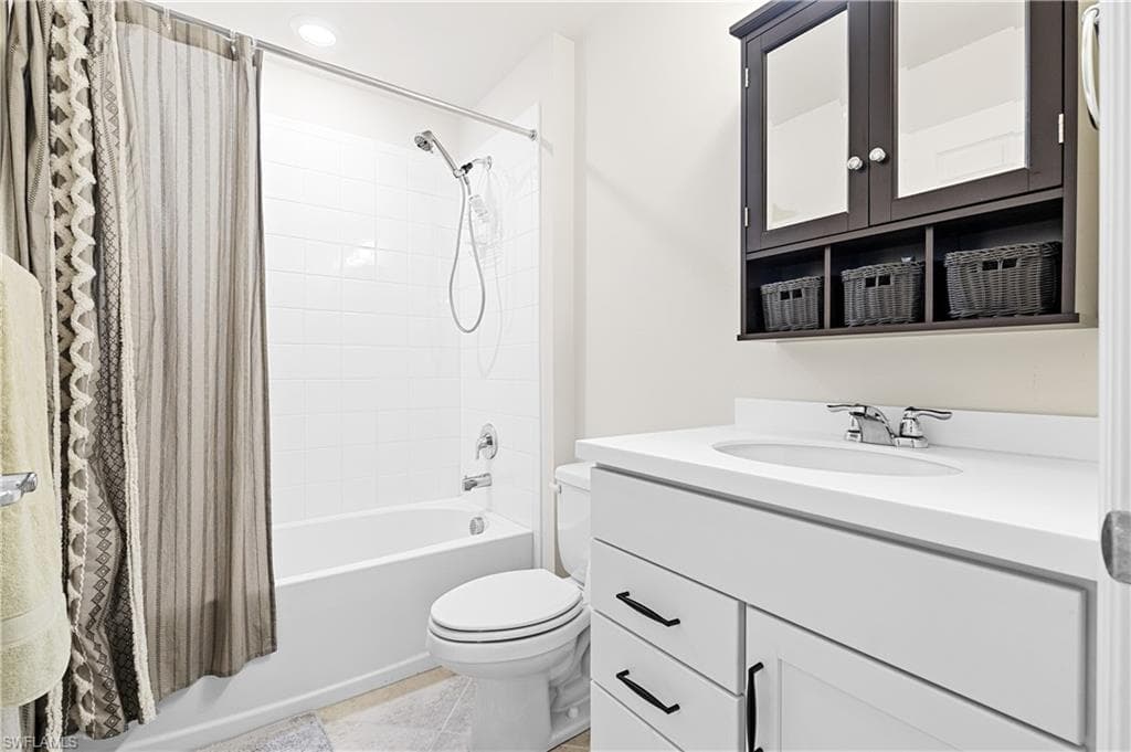 Bathroom featuring shower / bath combo with shower curtain, vanity, recessed lighting, and light tile patterned flooring