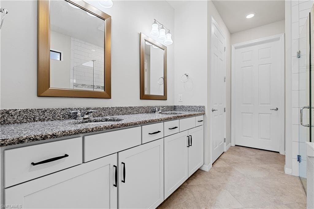 Bathroom featuring double vanity, a stall shower, and light tile patterned floors