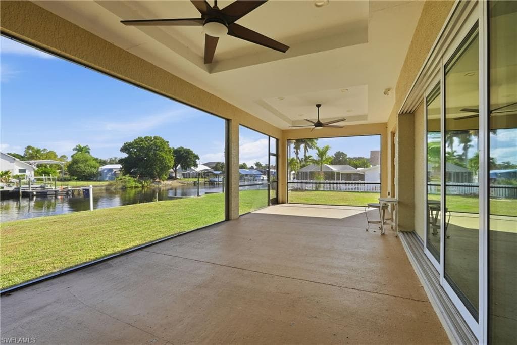Unfurnished sunroom featuring a ceiling fan, a water view, and a patio