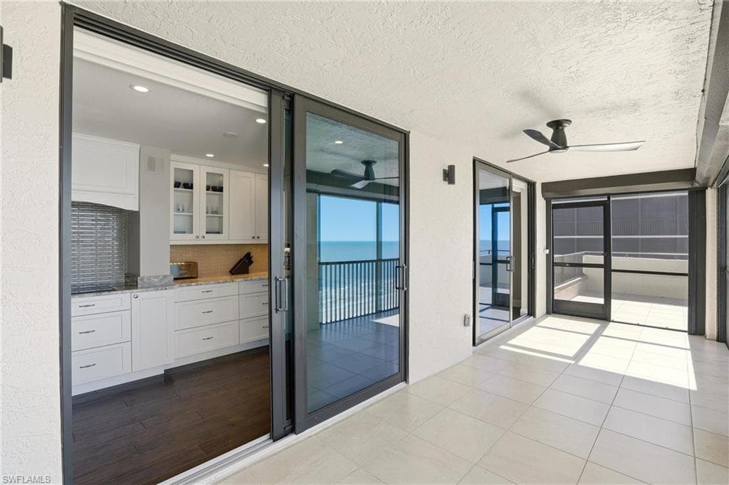 Balcony with ceiling fan, a water view, and a sunroom