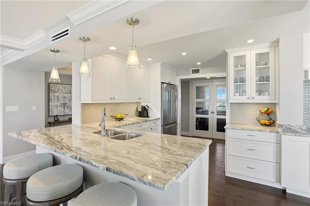 Kitchen with white cabinets, light stone countertops, a kitchen bar, and recessed lighting