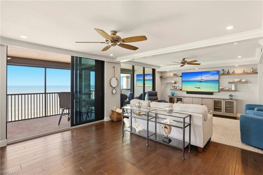 Living room with wood finished floors, crown molding, recessed lighting, and a water view