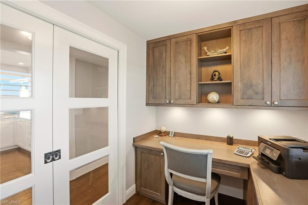 Office featuring built in desk and dark wood-style floors