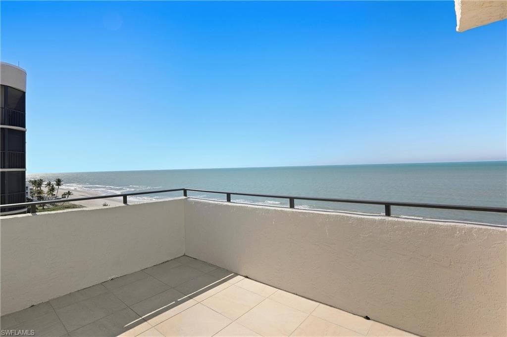 Balcony featuring view of water and beach