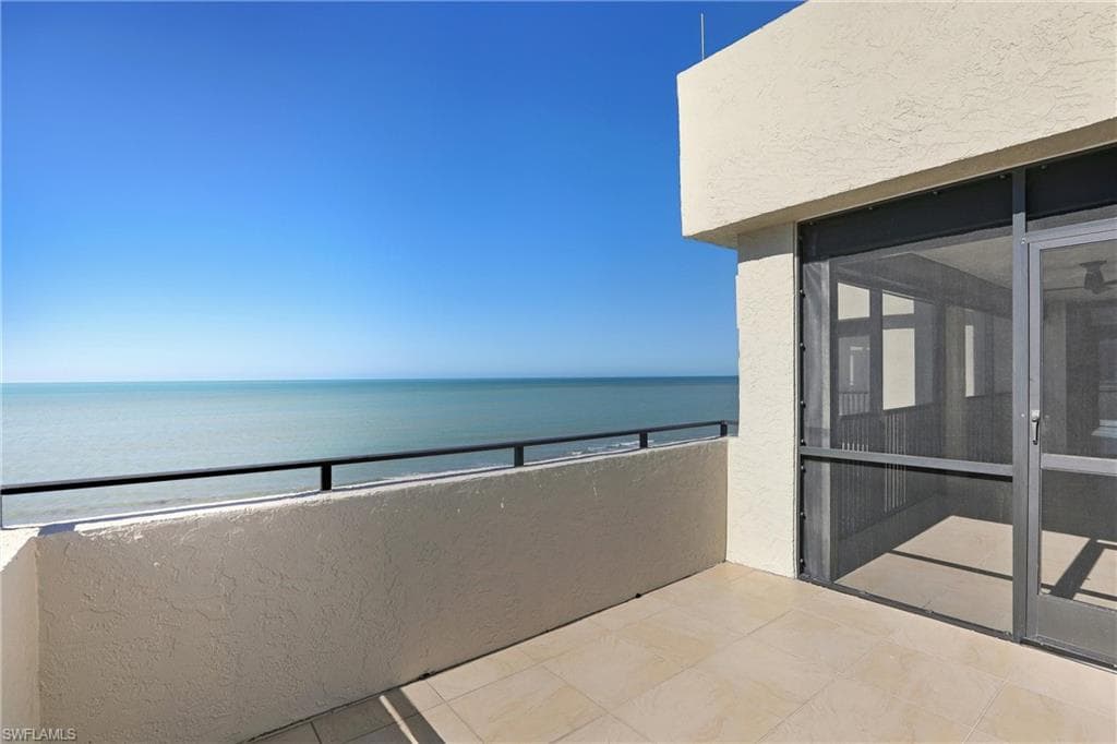 Balcony featuring view of water and beach