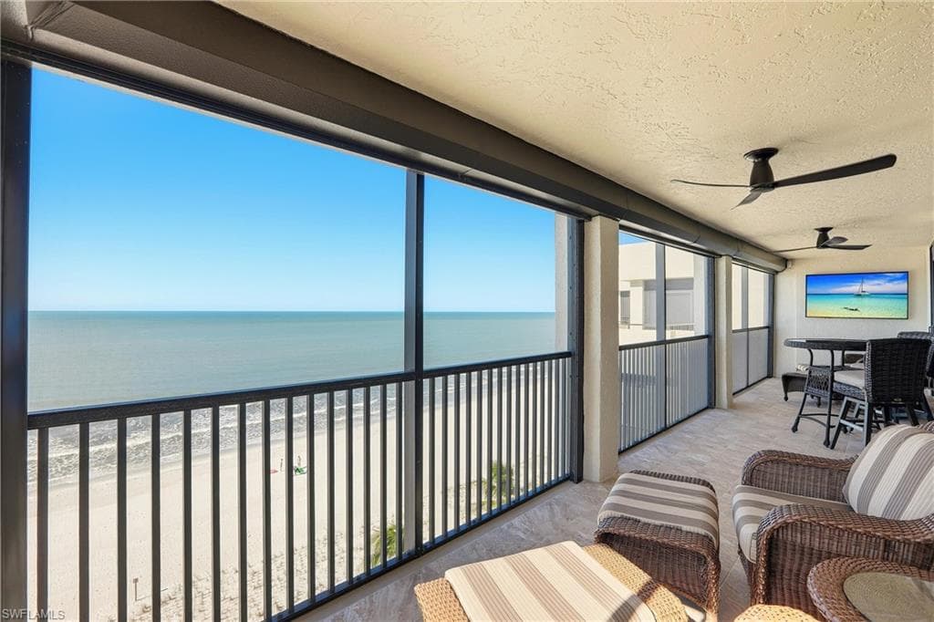 Sunroom featuring a ceiling fan, a balcony, a view of the beach, and outdoor dining space