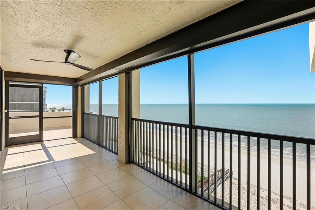 Unfurnished sunroom featuring view of water and beach