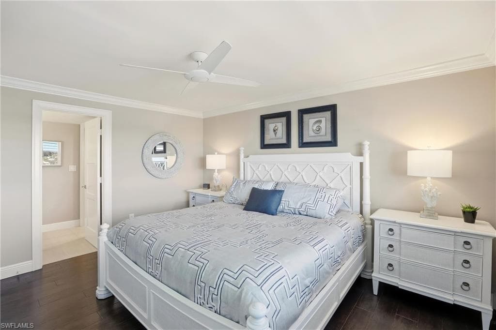 Bedroom with dark wood-style floors, ornamental molding, and a ceiling fan