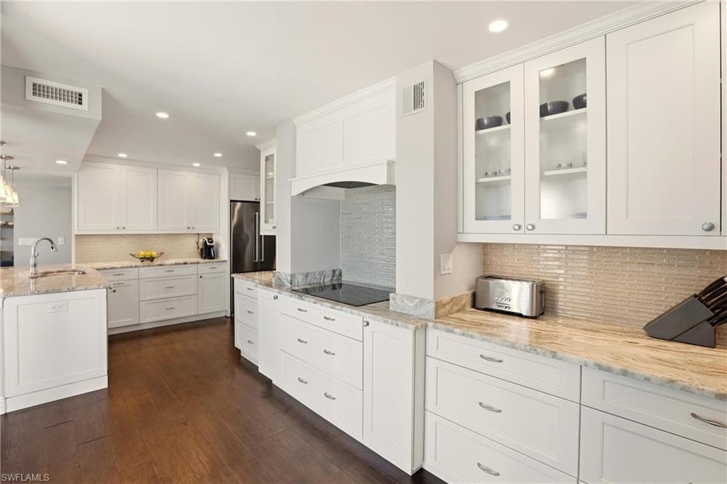 Kitchen with white cabinets, decorative light fixtures, light stone countertops, recessed lighting, and decorative backsplash