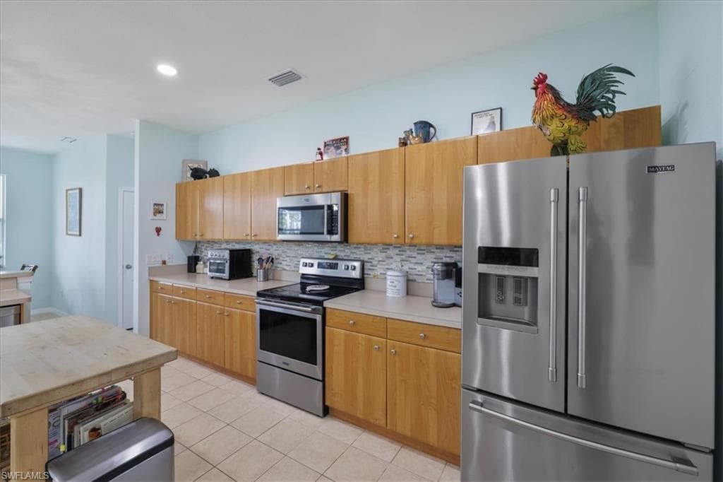 Kitchen featuring appliances with stainless steel finishes, light countertops, decorative backsplash, light tile patterned floors, and recessed lighting