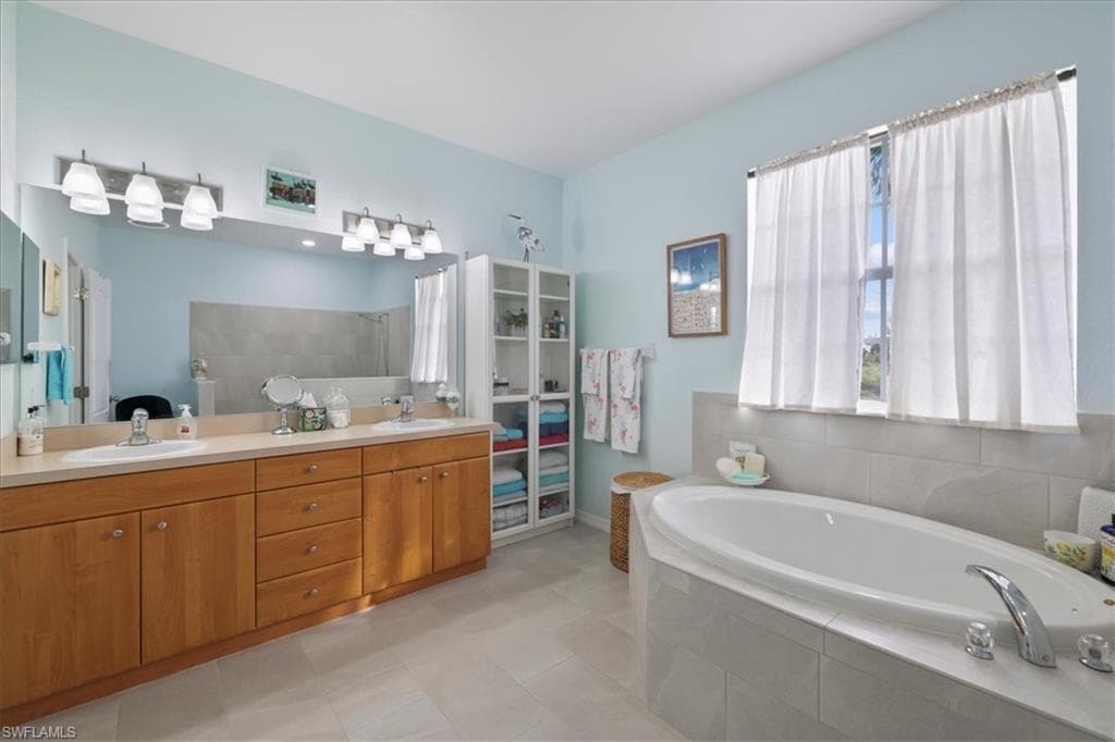 Bathroom with a bath, double vanity, and light tile patterned floors