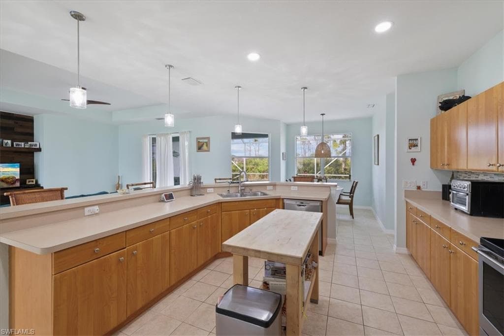 Kitchen featuring light countertops, hanging light fixtures, light tile patterned flooring, a large island, and recessed lighting