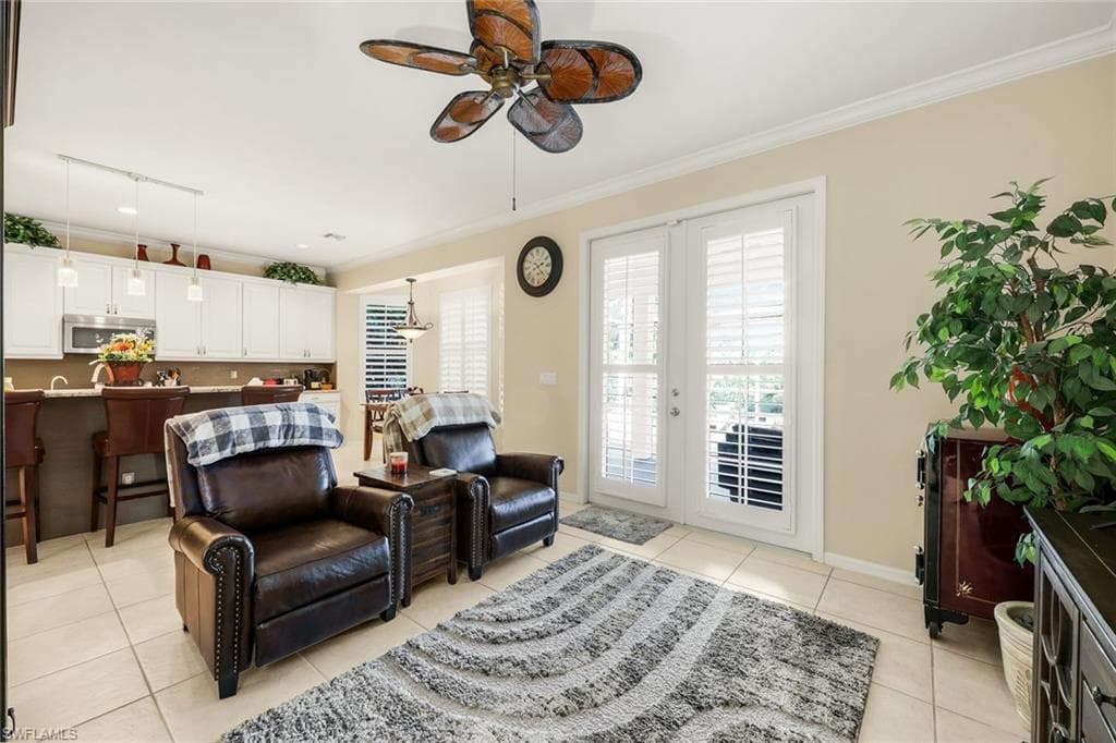 Living room featuring crown molding, ceiling fan, and light tile patterned flooring
