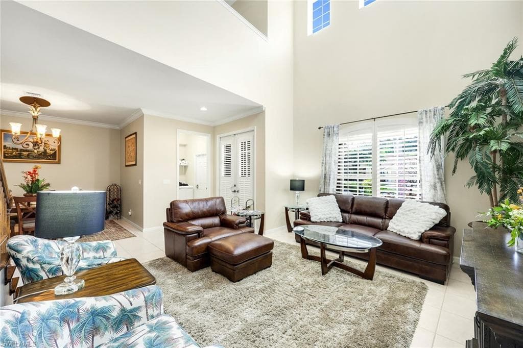 Living area with light tile patterned floors, crown molding, and a chandelier