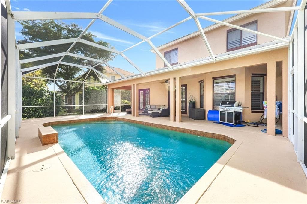 Swimming pool featuring a sunroom, outdoor lounge area, a patio area, area for grilling, and glass enclosure