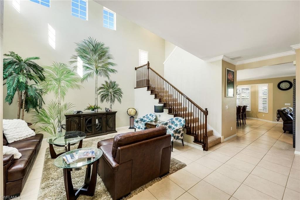 Living room featuring stairway, light tile patterned floors, and crown molding