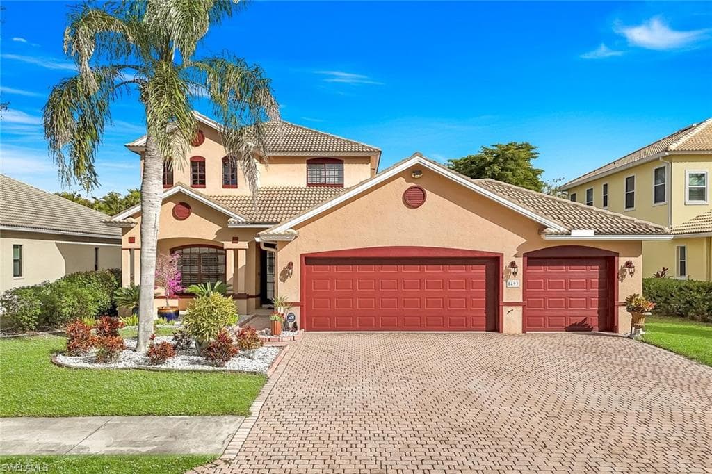 Mediterranean / spanish-style house with stucco siding, a tile roof, and decorative driveway
