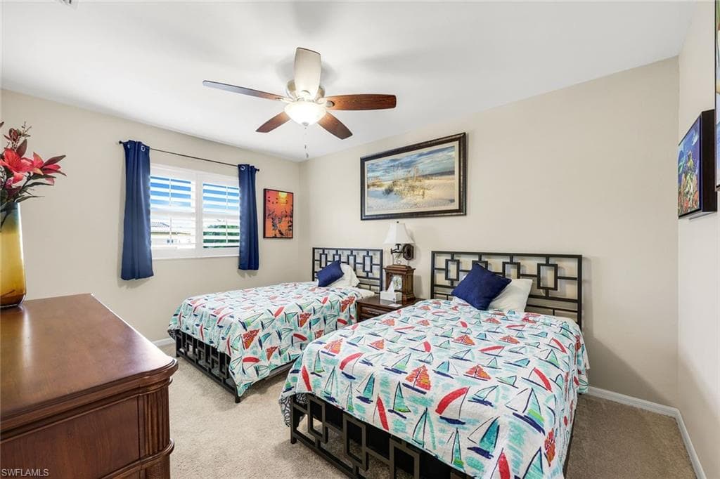 Carpeted bedroom featuring a ceiling fan and baseboards