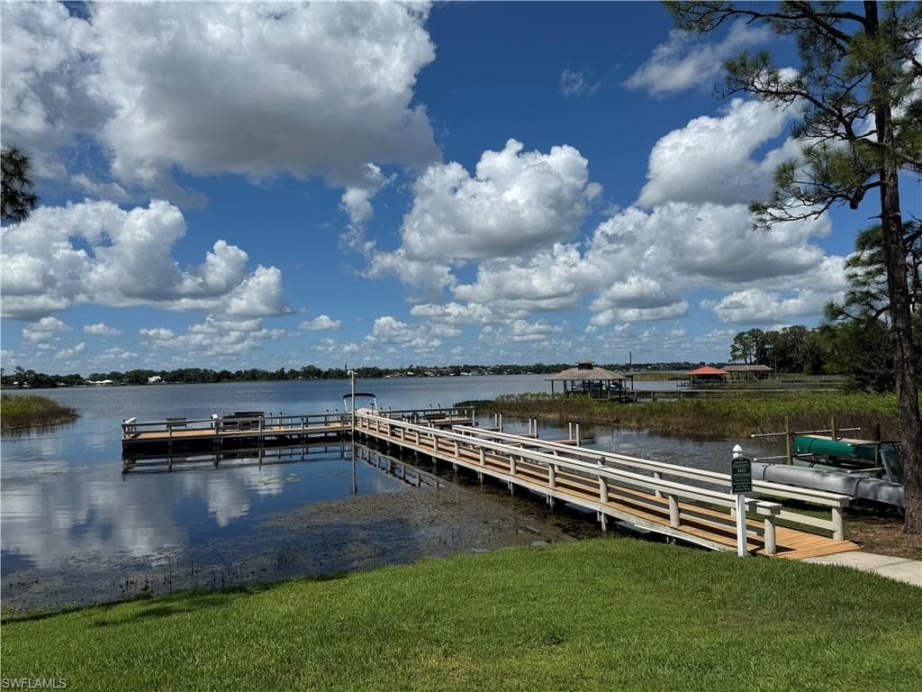 Dock area with a water view and a lawn