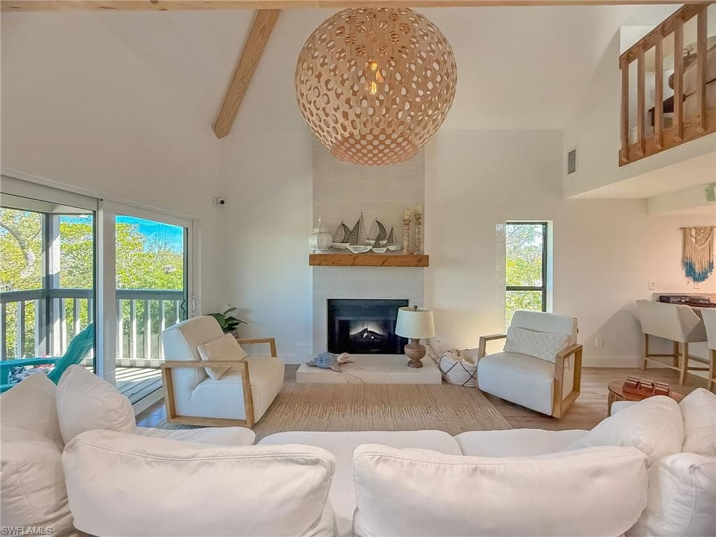 Living room with beamed ceiling, hardwood / wood-style flooring, and a high ceiling