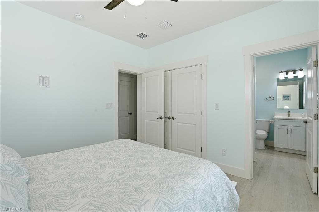 Light blue walls with white trim, wood-finish flooring, ceiling fan, and white paneled doors - Virtually Edited Image