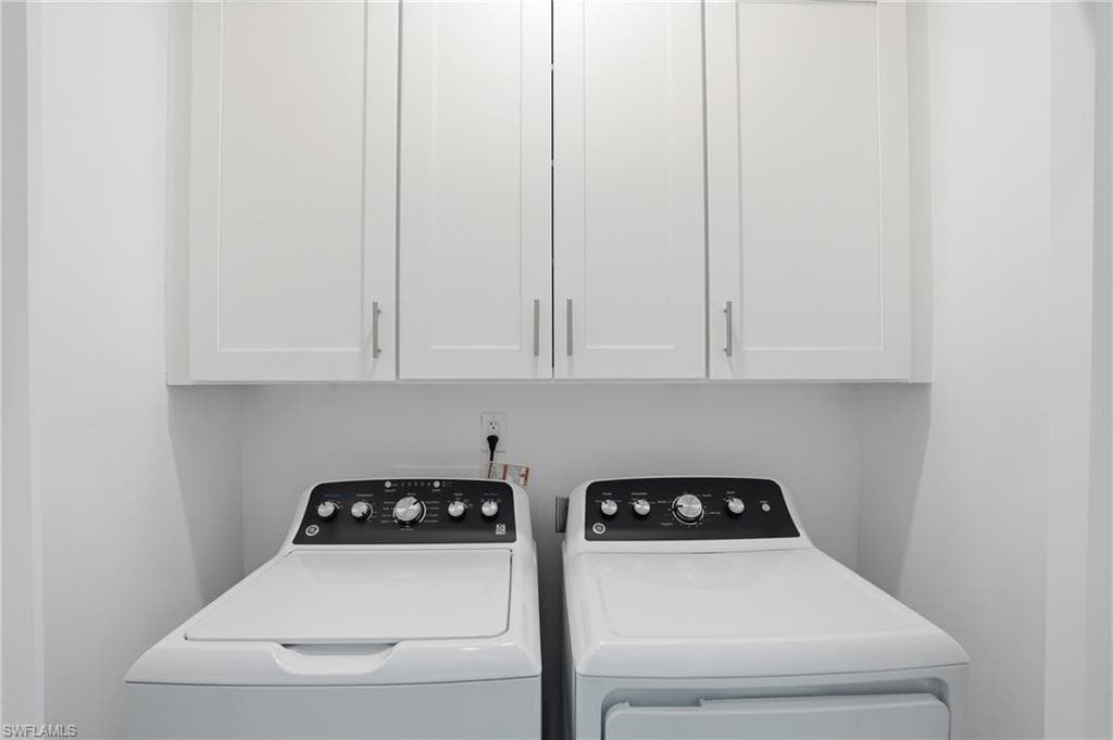 Dedicated laundry space featuring upper white cabinetry with brushed nickel hardware - Virtually Edited Image