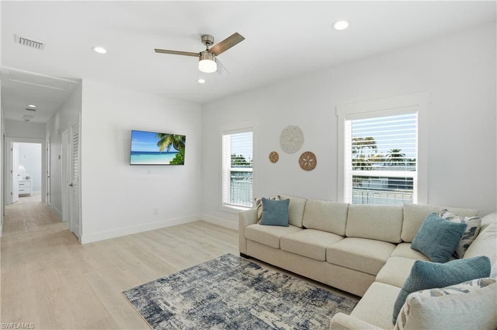 Open living area featuring light wood-finish flooring and recessed lighting - Virtually Edited Image