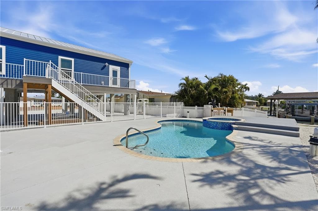 Outdoor oasis featuring a freeform pool, integrated spa, and spacious concrete patio - Virtually Edited Image