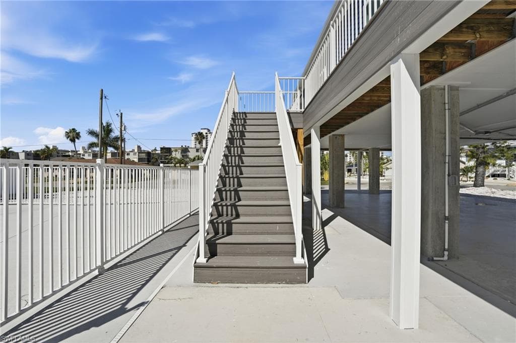 Exterior elevated entry featuring composite decking stairs and white railings - Virtually Edited Image