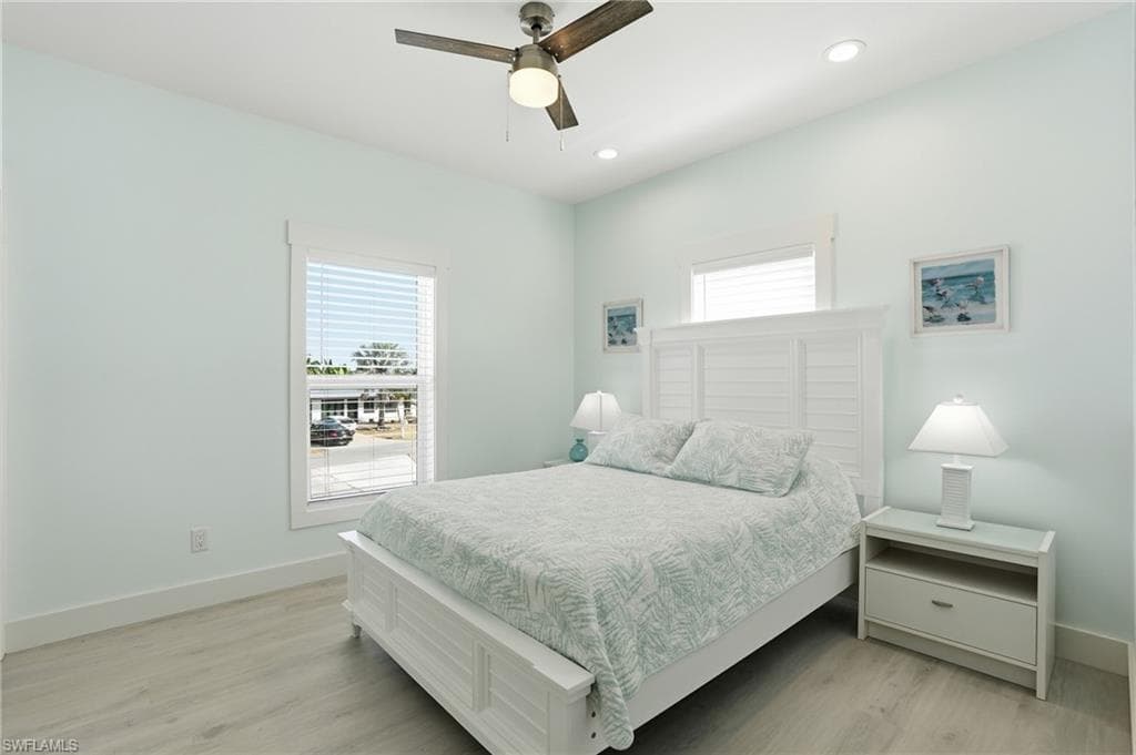 Primary Bedroom featuring Luxury vinyl flooring, two windows with blinds, recessed lighting, and a ceiling fan - Virtually Edited Image