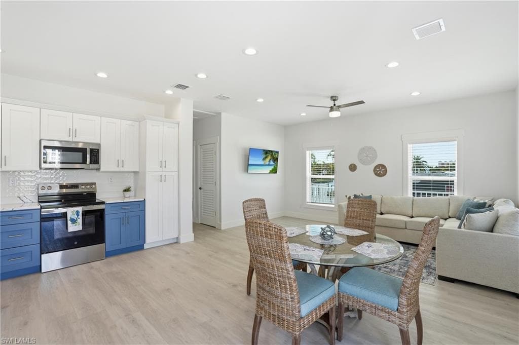 Open-concept living area featuring light wood-finish flooring, recessed lighting, and a ceiling fan - Virtually Edited Image