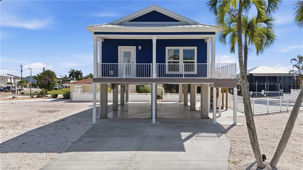Elevated coastal-style residence featuring a vibrant blue exterior and white trim - Virtually Edited Image
