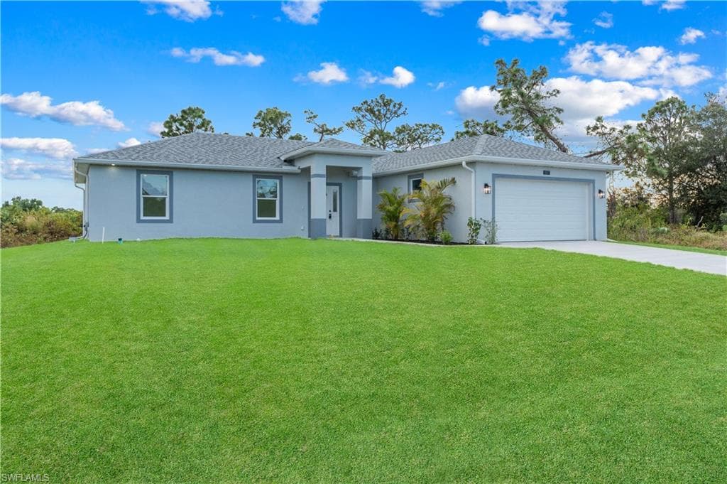 Ranch-style home with a front lawn, stucco siding, concrete driveway, an attached garage, and roof with shingles