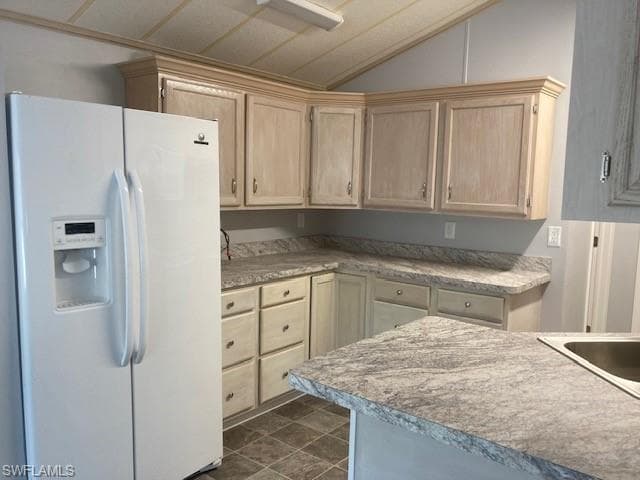 Kitchen featuring white refrigerator with ice dispenser, light brown cabinetry, and light countertops