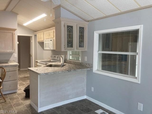 Kitchen with range with electric cooktop, light countertops, white microwave, a peninsula, and glass insert cabinets