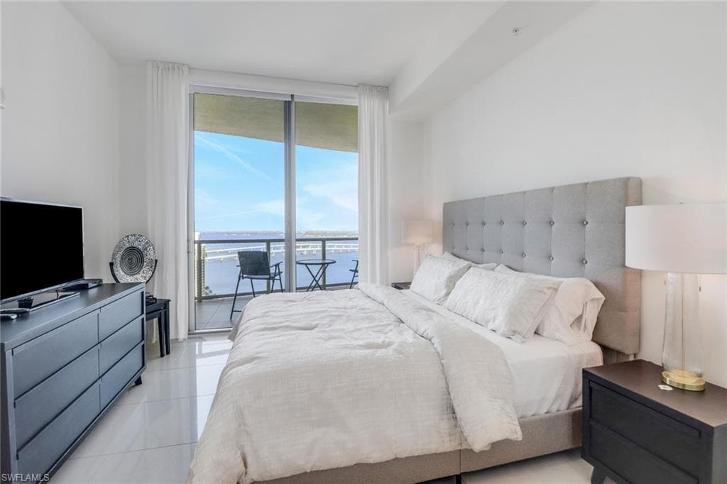 Bedroom featuring a wall of windows, access to exterior, and light tile patterned floors