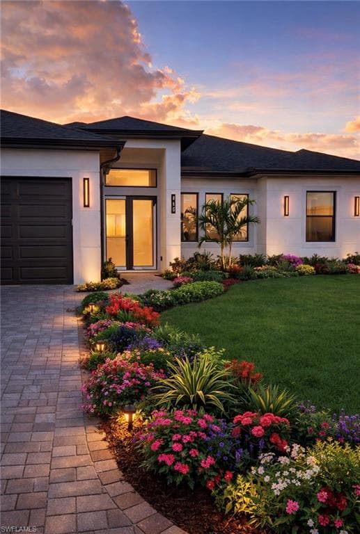 View of front of property featuring a garage, stucco siding, a front yard, and driveway