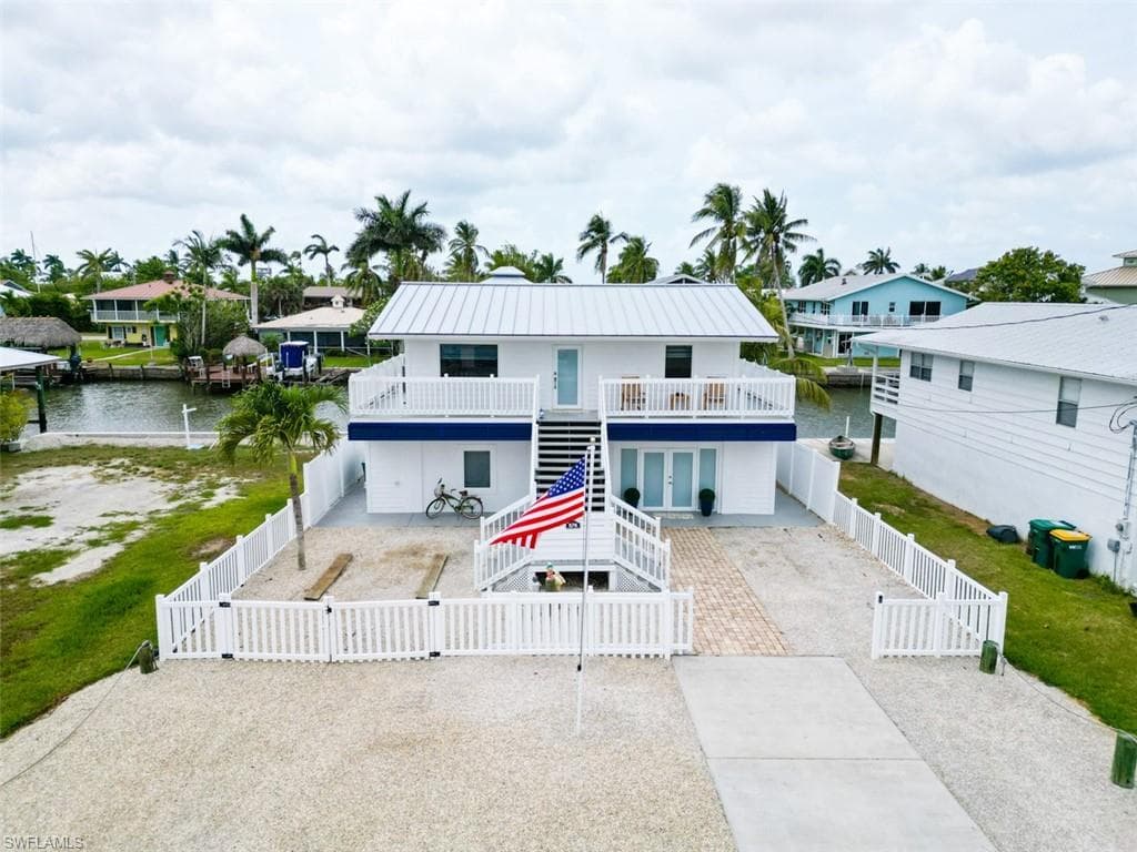 View of front of house featuring a gate, stairway, a fenced front yard, a patio area, and a deck with water view