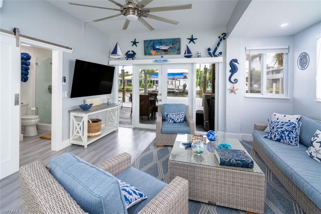 Living room with wood finished floors, plenty of natural light, ceiling fan, and french doors