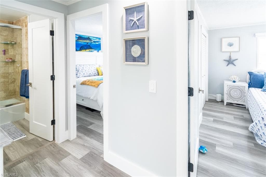 Hallway featuring light wood-type flooring and crown molding