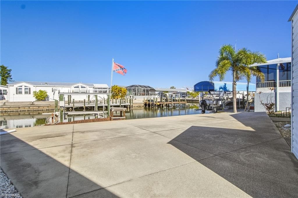 View of patio featuring a water view, a boat dock, and boat lift